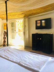 een slaapkamer met een bed en een flatscreen-tv bij CarthagŌ in Mbour