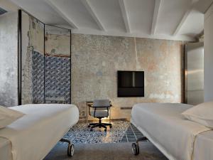 two beds in a room with a tv and a desk at Rhinoceros in Rome