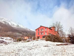 une maison rouge au sommet d'une colline enneigée dans l'établissement Hotel La Casa del Río, à Vilanova i la Geltrú