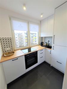a kitchen with white cabinets and a black dishwasher at Wera - klimatyczny apartament 300 m od plaży Brzeźno - AZW Gdańsk in Gdańsk