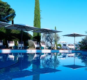 Relais Santa Chiara Hotel - Tuscany Charme في سان جيمنيانو: مسبح مع كراسي ومظلات