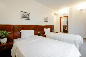 2 Betten in einem Hotelzimmer mit weißer Bettwäsche in der Unterkunft White Palace 2 in Thái Bình