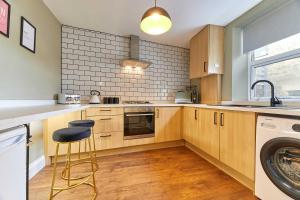 a kitchen with wooden cabinets and a washer and dryer at Host & Stay - The Blacksmiths in Warkworth