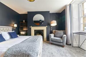 a bedroom with a bed and a chair and a mirror at Host & Stay - The Blacksmiths in Warkworth