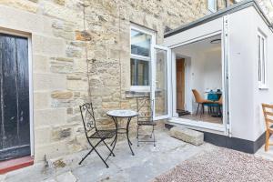 eine Terrasse mit Stühlen und einem Tisch und einem Fenster in der Unterkunft Host & Stay - The Blacksmiths in Warkworth