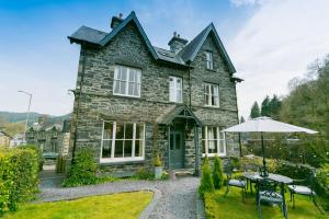 a stone house with a table and an umbrella at Bryn Afon in Betws-y-coed