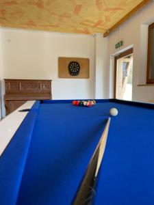 a blue pool table in a room with a clock on the wall at Sportgästehaus Unterberg in Kössen