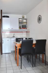 a kitchen with a wooden table and black chairs at Granges 9 - Appartement vue époustouflante, au pied des pistes Domaine Alpe d'Huez in Villard-Reculas