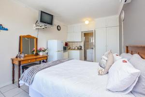 a bedroom with a bed and a desk and a kitchen at Paradise View in Knysna