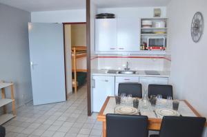 a kitchen with a table and chairs and a kitchen with white cabinets at Granges 9 - Appartement vue époustouflante, au pied des pistes Domaine Alpe d'Huez in Villard-Reculas