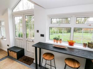 a kitchen with two stools and a counter with windows at Little Bobbins in Saundersfoot