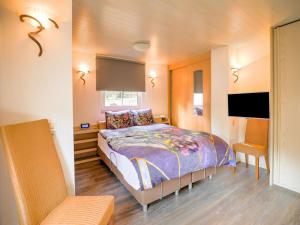 een slaapkamer met een bed en een stoel erin bij Charming Holiday Home in Meijel in a Recreation Park in Meijel