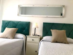 een slaapkamer met 2 bedden en een spiegel aan de muur bij GATU PREMIUM Vista Infinita 1ªlinea mar WIFI, AIRE ACC in Cádiz