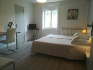 a bedroom with a bed and a desk and a window at Le Relais de Ceilhes in Ceilhes-et-Rocozels