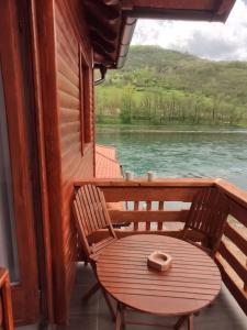 LjubovijaにあるApartmani ODMOR NA DRINIの湖の景色を望むポーチ(椅子付)