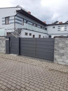 ein schwarzer Zaun vor einem weißen Haus in der Unterkunft Apartamenty U Elizy in Kołobrzeg
