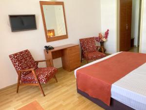a bedroom with a bed and two chairs and a mirror at Hotel Tomis Neptun in Neptun