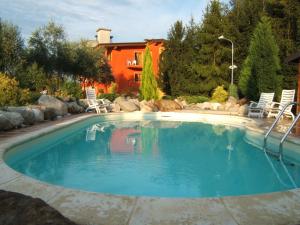 a swimming pool in a yard with chairs and a house at Hotel Empire Resort in Iseo