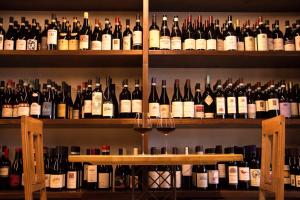een plank gevuld met veel flessen wijn bij L'Aromatario in Neive