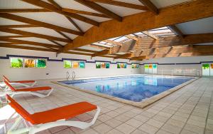 a large swimming pool with orange chairs in a building at Vacancéole - Résidence Le Palmyra Golf in Cap d'Agde