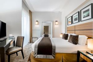 una camera d'albergo con letto, scrivania e TV di Hotel Ambasciatori a Rimini