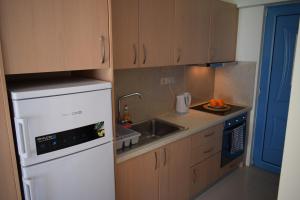 a kitchen with a white refrigerator and a sink at Ammos & Thalassa in Vasiliki
