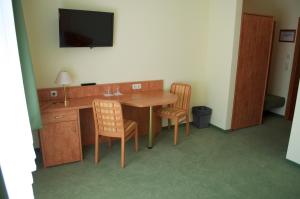 a room with a table and chairs and a television at Gasthof & Pension Zum Himmel in Rubenow