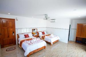 two beds in a room with white walls and wooden floors at HOÀNG KIM HOTEL in Liên Trì (3)