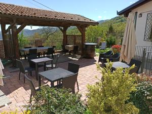 un patio con mesas, sillas y una pérgola en Trattoria della Posta en Peveragno