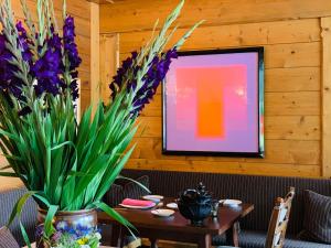 a table with purple flowers and a painting on a wall at Kristiania Lech in Lech am Arlberg