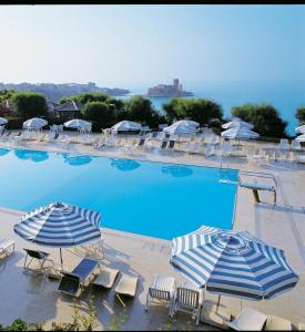 uma grande piscina com guarda-sóis e cadeiras em iGV Club Vacanze Le Castella em Le Castella
