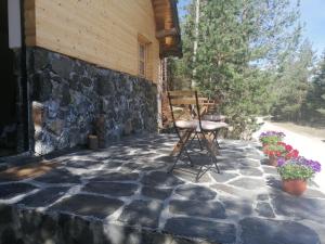 a stone patio with a chair and flowers at Garac Zlatibor Vikendica in Zlatibor
