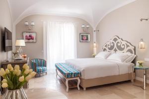 a bedroom with a white bed and a table and chairs at Hotel Don Ferrante in Monopoli