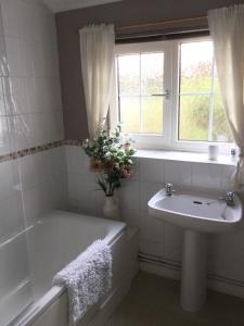 a bathroom with a tub and a sink and a window at The Old House Cottages in Nether Stowey