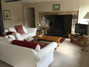 a living room with white couches and a fireplace at The Old House Cottages in Nether Stowey