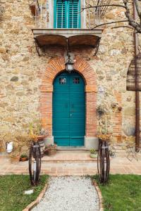 una porta blu in un edificio di mattoni con muro di pietra di Angolo Divino Tuscany a Lucignano