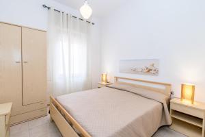 a white bedroom with a bed and two lamps at Casa Spiaggia Molo 2 in Isola Rossa