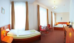 a room with two beds and a table and chairs at Wellness Hotel Central in Klatovy