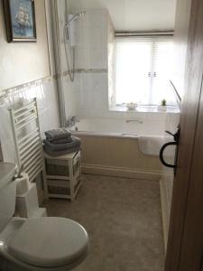 a bathroom with a tub and a toilet and a window at The Old House Cottages in Nether Stowey +31 photos