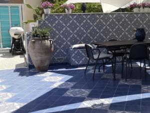 eine Terrasse mit einem Tisch und Stühlen auf einem blauen Fliesenboden in der Unterkunft Casa Vacanze Ibiscus in Alcamo Marina