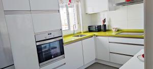 eine weiße Küche mit Spüle und Herd in der Unterkunft Piso 100 metros del Centro del Pueblo 6 kilómetros de la PLAYA La BARROSa in Chiclana de la Frontera