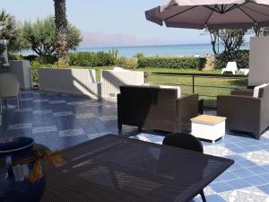 eine Terrasse mit einem Tisch, Stühlen und einem Sonnenschirm in der Unterkunft Casa Vacanze Ibiscus in Alcamo Marina