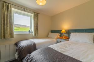 two beds in a room with a window at 1 Riverside Cottage in Burnsall