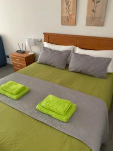 Una cama verde con dos toallas verdes. en Marsin Playa 210 Vivienda Vacacional, en Las Palmas de Gran Canaria