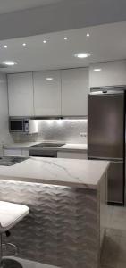 a kitchen with white cabinets and a stainless steel refrigerator at Tus vacaciones en el corazón de Alicante! in Alicante