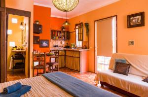 1 dormitorio con paredes de color naranja, 1 cama y cocina en Casa Conchilla, La Casita, en Valle Gran Rey