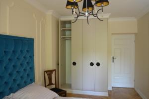 1 dormitorio con cabecero azul y lámpara de araña en Apartament Orchidea Centrum, en Varsovia