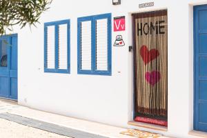 un edificio blanco con puertas azules y corazones pintados en él en Casita Corazón en Caleta de Sebo