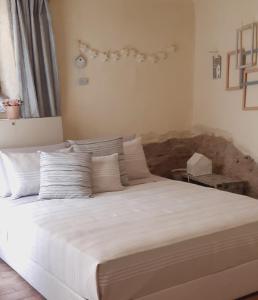 1 dormitorio con 1 cama grande con sábanas y almohadas blancas en Tavernetta vicino Lago Trasimeno, en Magione