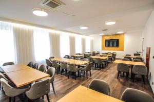 a conference room with tables and chairs and a screen at Hotel Mariel Znojmo in Znojmo
